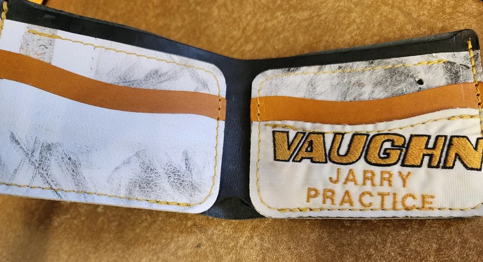 Close-up of a worn leather wallet with 'Vaughn Jarry Practice' branding on a brown background.